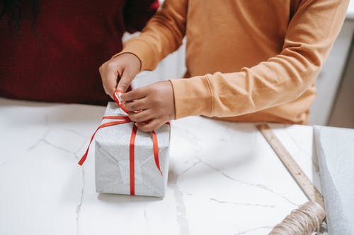 作物民族儿童在家里的礼品盒上绑丝带 · 免费素材图片