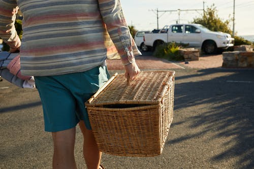 蓝色牛仔短裤的人拿着布朗编织的篮子 · 免费素材图片