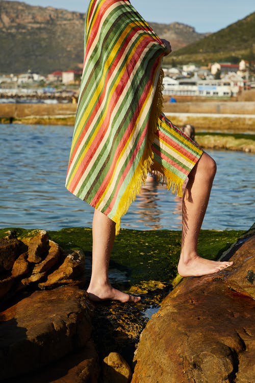 绿色白色和粉红色的裙子站在水附近的棕色岩石上的女人 · 免费素材图片