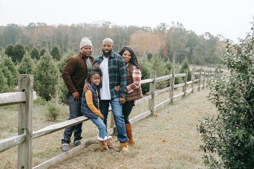 拥抱在篱芭附近的微笑的黑人家庭在乡下 · 免费素材图片