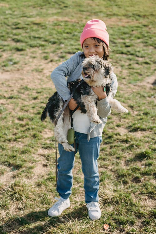 微笑的族裔孩子在草坪上拥抱约克夏犬 · 免费素材图片