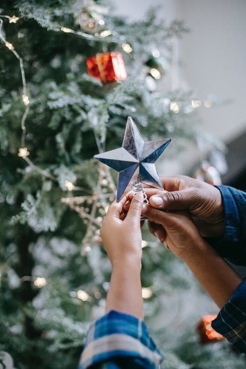黑爸爸把星星放在带孩子的圣诞树上 · 免费素材图片