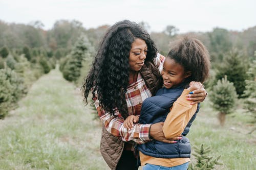 拥抱女儿的愉快的黑人母亲在林场 · 免费素材图片