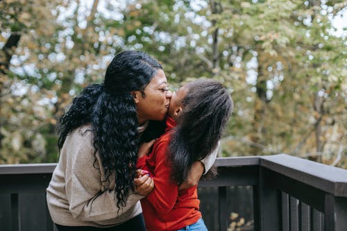 快乐的黑人母亲，在阳台上亲吻女儿 · 免费素材图片