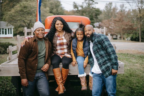 性格开朗的非洲裔美国家庭拥抱附近农场上的车辆 · 免费素材图片