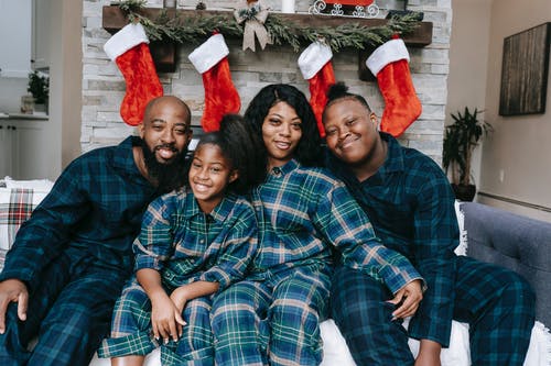 圣诞节假期期间，穿着睡衣的快乐黑人家庭在沙发上 · 免费素材图片