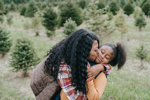 快乐的黑人母亲拥抱和亲吻女儿 · 免费素材图片