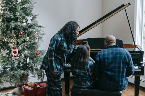 在与圣诞树的舒适房间里弹钢琴的黑人家庭 · 免费素材图片