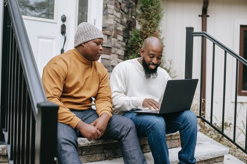 有儿子的快乐的黑人商人浏览膝上型计算机 · 免费素材图片