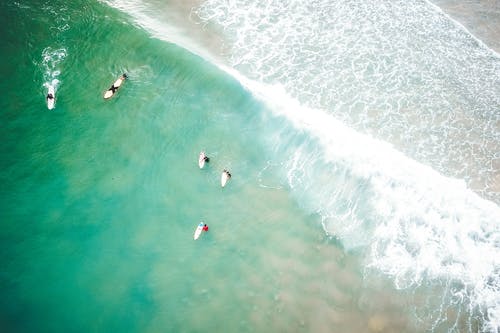 不可识别的冲浪者，在阳光明媚的日子挥舞着大海 · 免费素材图片