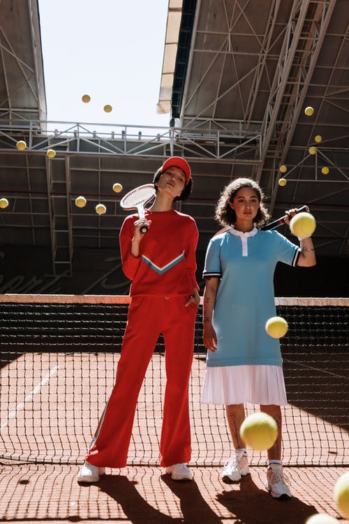 2名拿着黄色网球拍的红色和蓝色长袖衬衫的女人 · 免费素材图片