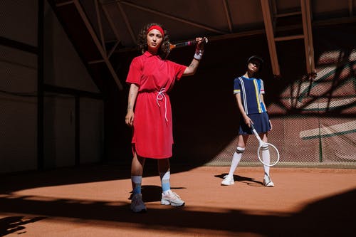 2名穿着红色和蓝色连衣裙的女人拿着白色的网球拍 · 免费素材图片