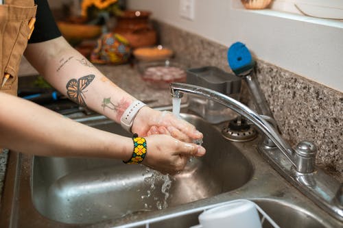 黄色和黑色手链洗手在水槽上的人 · 免费素材图片