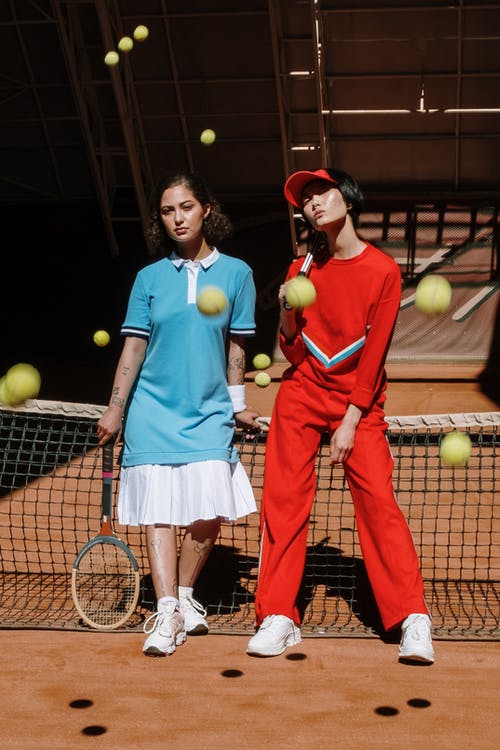 2名穿着蓝色和红色无袖连衣裙的女人拿着网球拍 · 免费素材图片