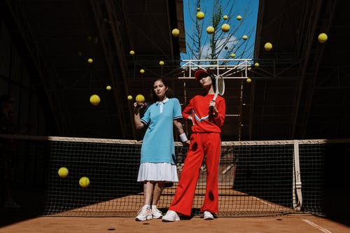 拿着黄色和绿色网球拍的红色长袖礼服的妇女 · 免费素材图片