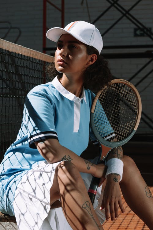 蓝色和白色阿迪达斯船员的脖子t恤，拿着白色和蓝色网球拍的女人 · 免费素材图片