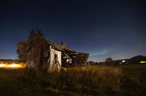 被遗弃的木制谷仓，在繁星密布的夜空，绿草如茵的地形上 · 免费素材图片