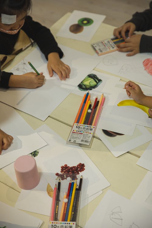 不可识别的学龄前种族儿童在上课时画在纸上 · 免费素材图片