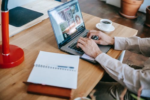 白色长袖衬衫，棕色的木桌上使用macbook Pro的人 · 免费素材图片