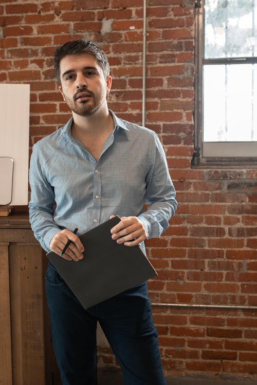拿着黑色平板电脑的蓝色衬衫的男人 · 免费素材图片