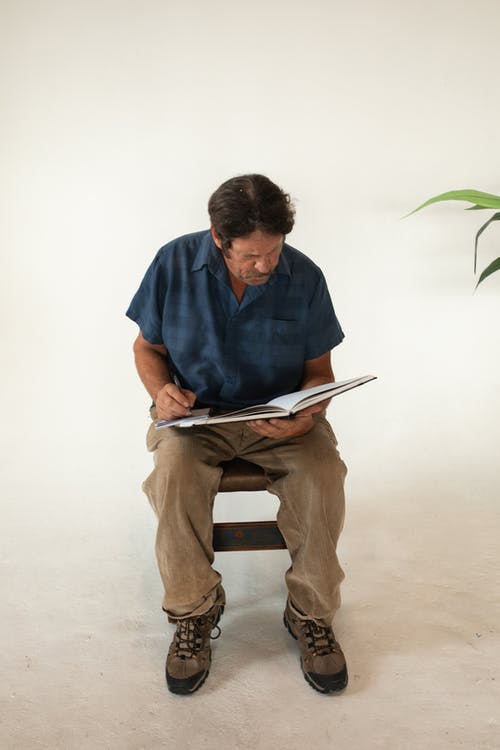 衬衫和棕色的裤子，坐在棕色的木座椅上的蓝色按钮的人 · 免费素材图片