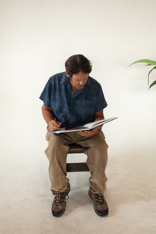 衬衫和棕色的裤子，坐在棕色的木座椅上的蓝色按钮的人 · 免费素材图片