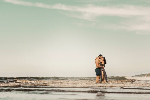 男人和女人站在海滩上 · 免费素材图片
