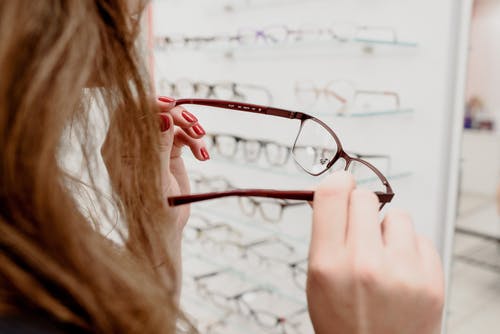 女人在商店里选择眼镜与各种轮辋 · 免费素材图片