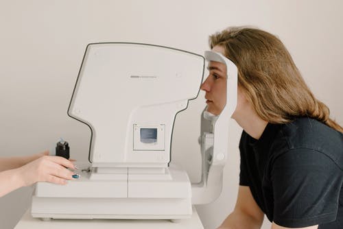无法识别的眼科医生在视力筛查仪上扫描女人的眼睛 · 免费素材图片