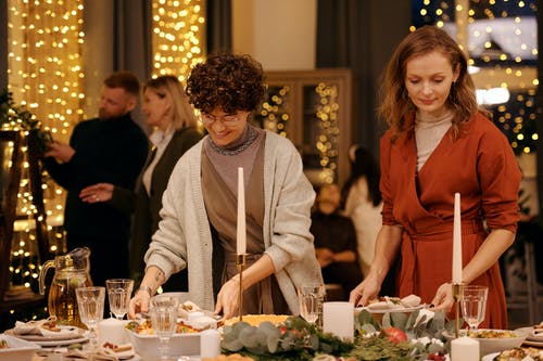 两名妇女准备圣诞节晚餐的餐桌布置 · 免费素材图片