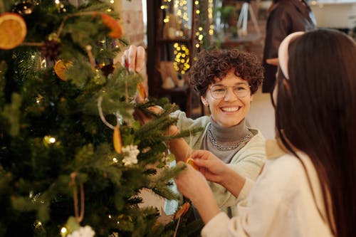 母亲和女儿装饰一棵圣诞树 · 免费素材图片