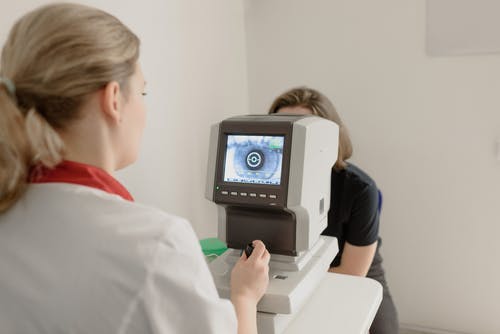 匿名眼科医生在筛眼仪上检查患者的视力 · 免费素材图片