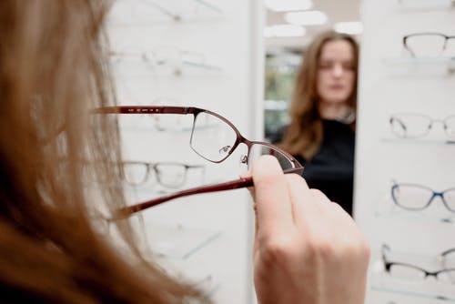 女人采摘眼镜以纠正存储区中的视力 · 免费素材图片