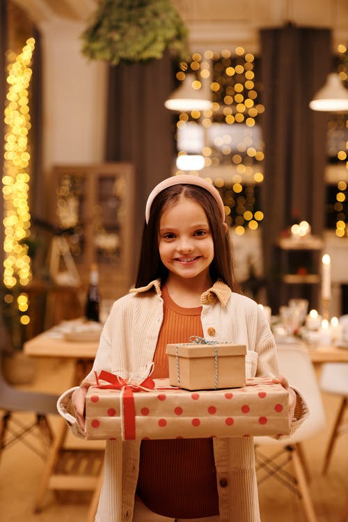 浅焦点的女孩微笑着拿着她的圣诞礼物 · 免费素材图片