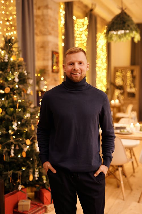 黑色高领长袖衬衫站在圣诞树旁的人 · 免费素材图片