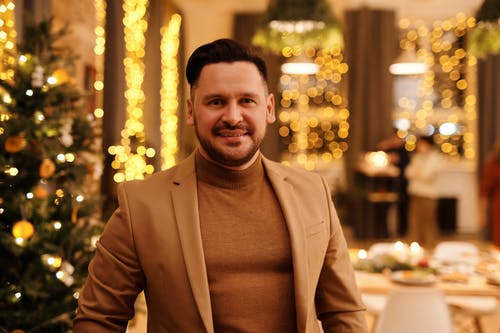 棕色外套的男人微笑着看着相机 · 免费素材图片