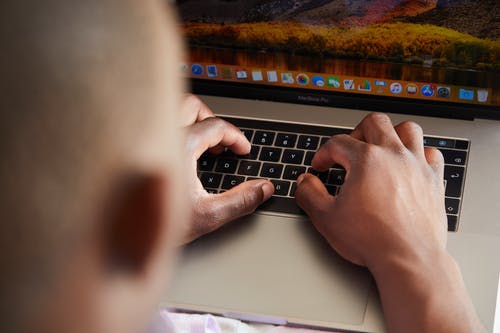 黑人与明亮的桌面使用笔记本电脑 · 免费素材图片