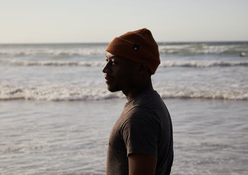 梦幻般的黑人男性游客在海洋附近的针织帽 · 免费素材图片