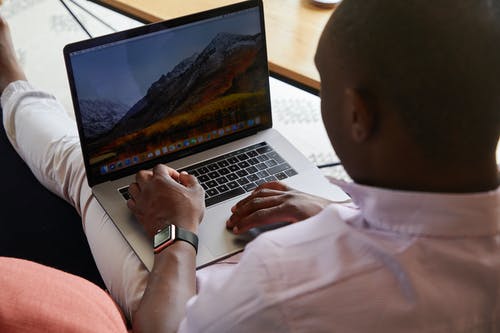 黑人男子与智能手表使用笔记本电脑的触摸板 · 免费素材图片