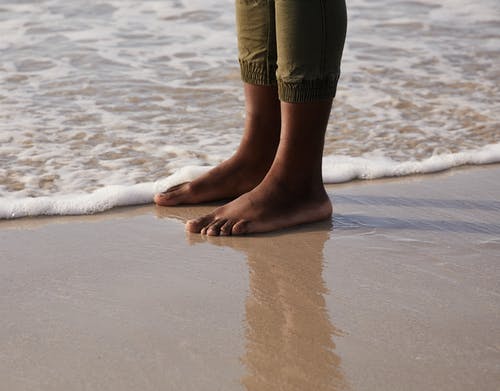 沙滩海洋海岸上的不露面赤脚黑人旅行者 · 免费素材图片