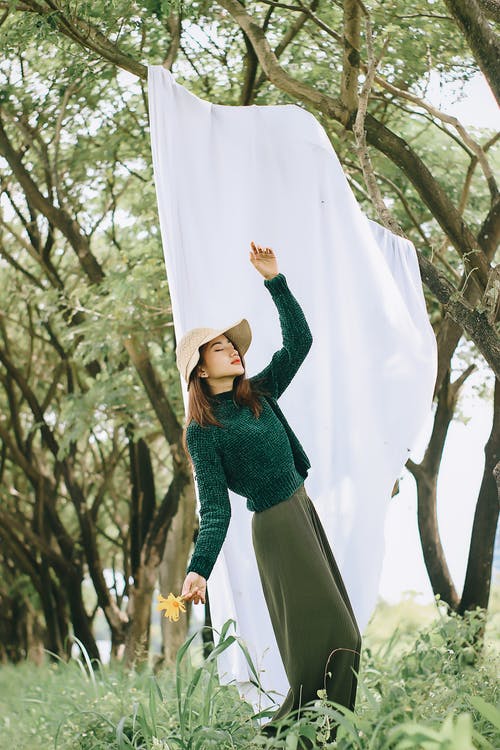 反对白布在绿树林中的坦然女人 · 免费素材图片