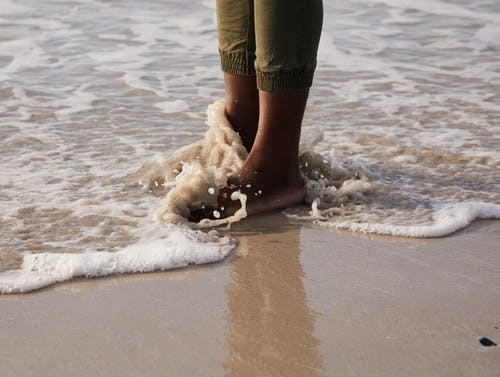 作物黑人站在湿海岸上 · 免费素材图片