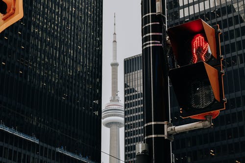 红色交通信号灯和摩天大楼之间的电视塔 · 免费素材图片