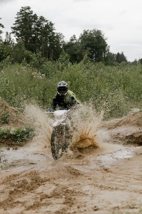 男子骑越野摩托车越野摩托车在土路上 · 免费素材图片