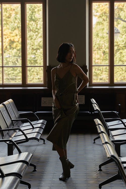 站在窗户附近的棕色无袖连衣裙的女人 · 免费素材图片