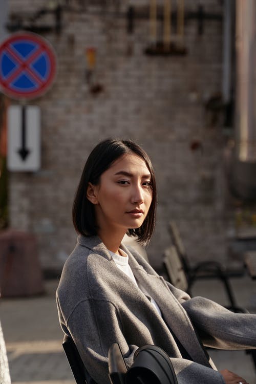 灰色连帽衫坐在棕色的木凳上的女人 · 免费素材图片