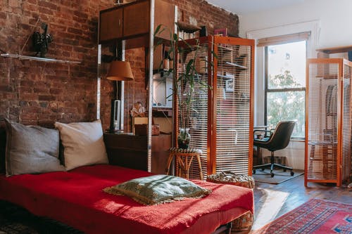 舒适的卧室，舒适的床和靠近砖墙的工作区 · 免费素材图片