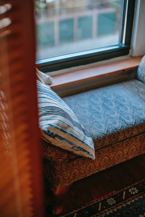 靠近窗户和地毯的软垫软垫 · 免费素材图片