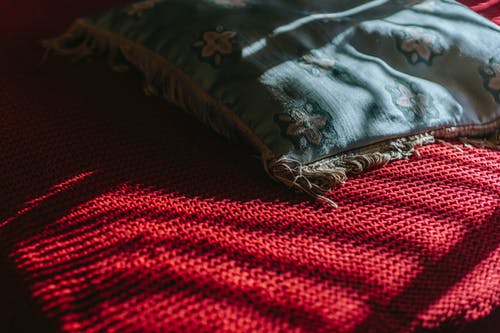 枕头放在红色的毯子上 · 免费素材图片