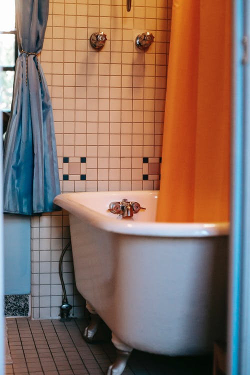 带有橙色窗帘和瓷砖地板和墙壁的浴室的内部 · 免费素材图片
